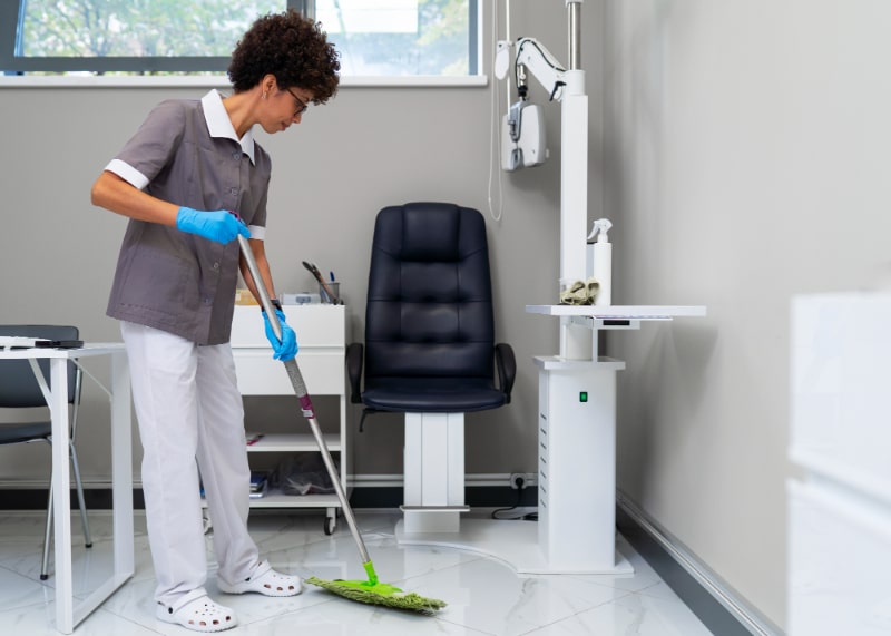 A woman cleaning the doctor's office with a mop